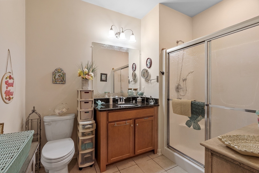 200 Martins Landing, Unit 102 North Reading, MA 01864 - Photo 18 of 33 a bathroom with a granite countertop toilet a sink and a mirror