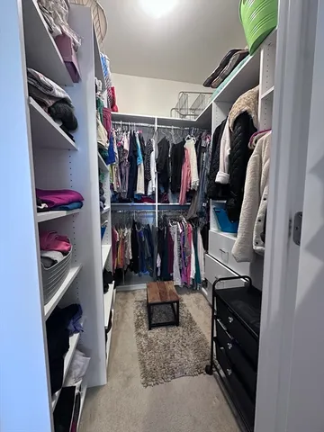 a view of walk in closet with clothes and shoes
