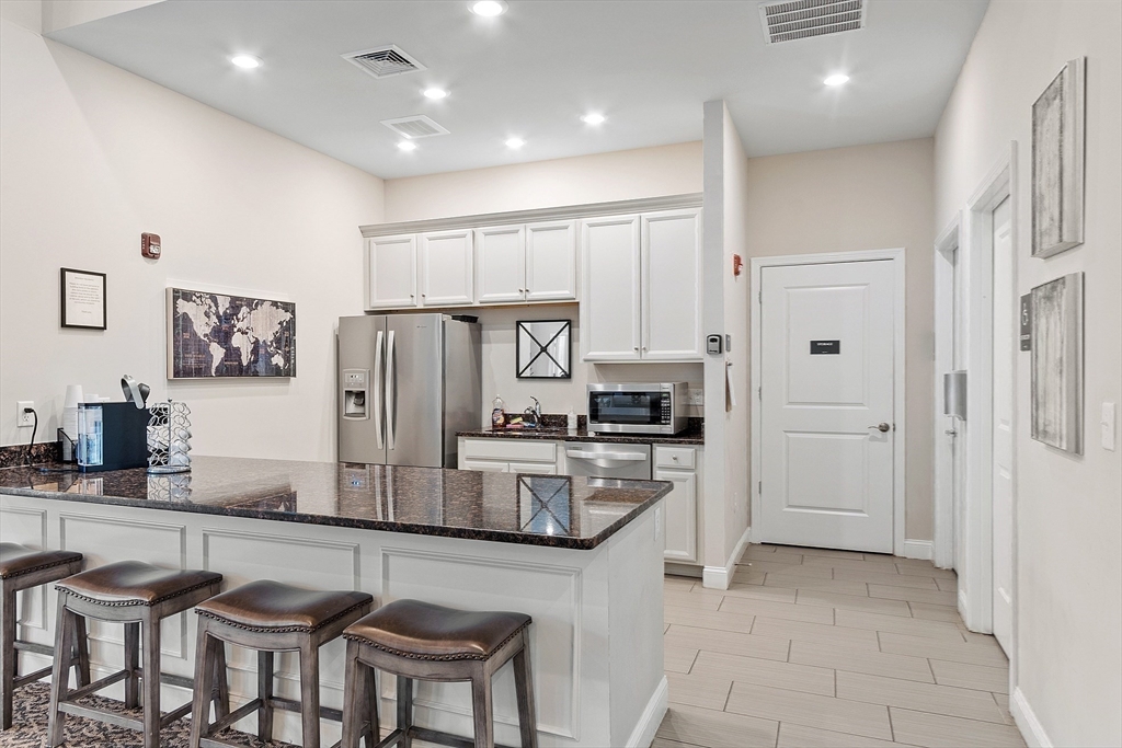 200 Martins Landing, Unit 102 North Reading, MA 01864 - Photo 30 of 33 a kitchen with stainless steel appliances granite countertop a refrigerator and a stove top oven