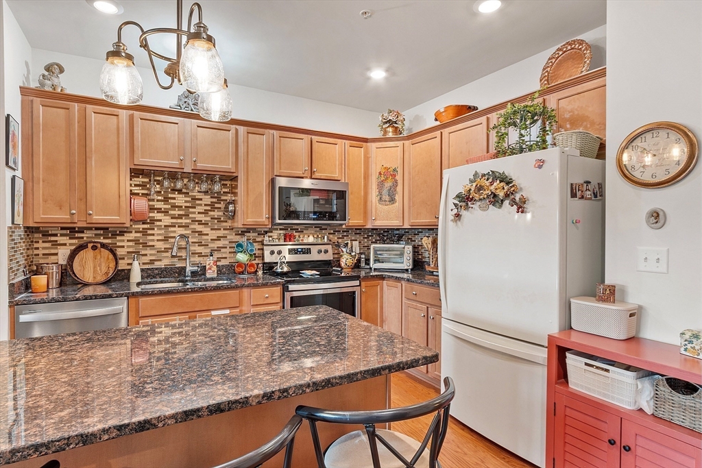 200 Martins Landing, Unit 102 North Reading, MA 01864 - Photo 10 of 33 a kitchen with stainless steel appliances granite countertop a refrigerator a stove top oven a sink and dishwasher