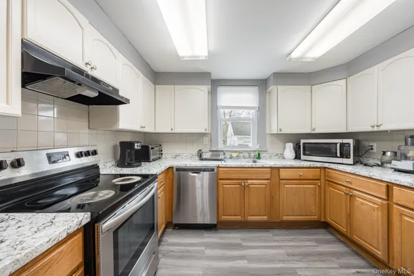 a kitchen with stainless steel appliances granite countertop a sink a stove a refrigerator cabinets and a window