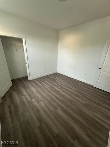 an empty room with wooden floor and mirror