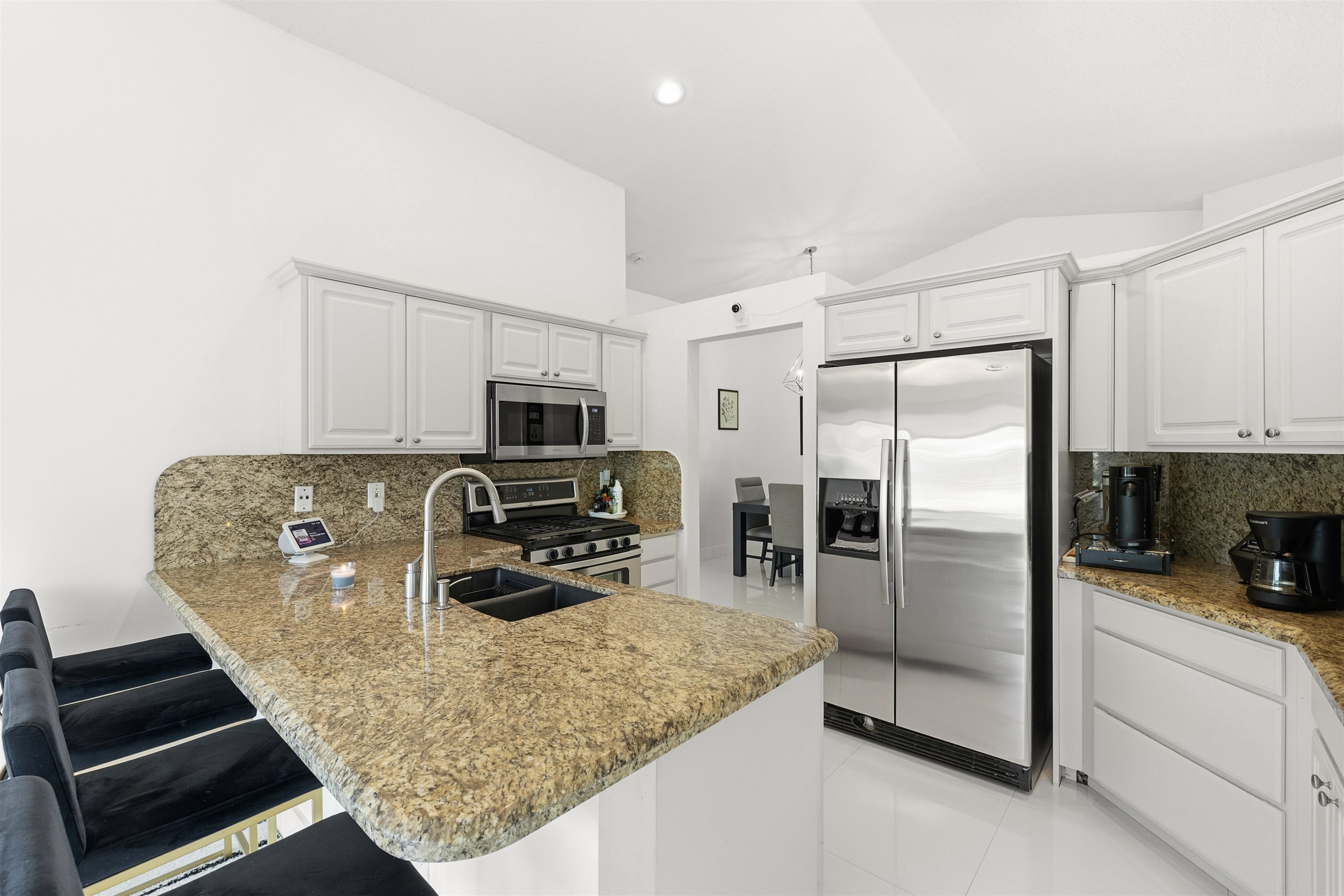 75 Gables Boulevard Weston, FL 33326 - Photo 10 of 29 Kitchen featuring backsplash, stainless steel appliances, vaulted ceiling, a peninsula, and light stone counters