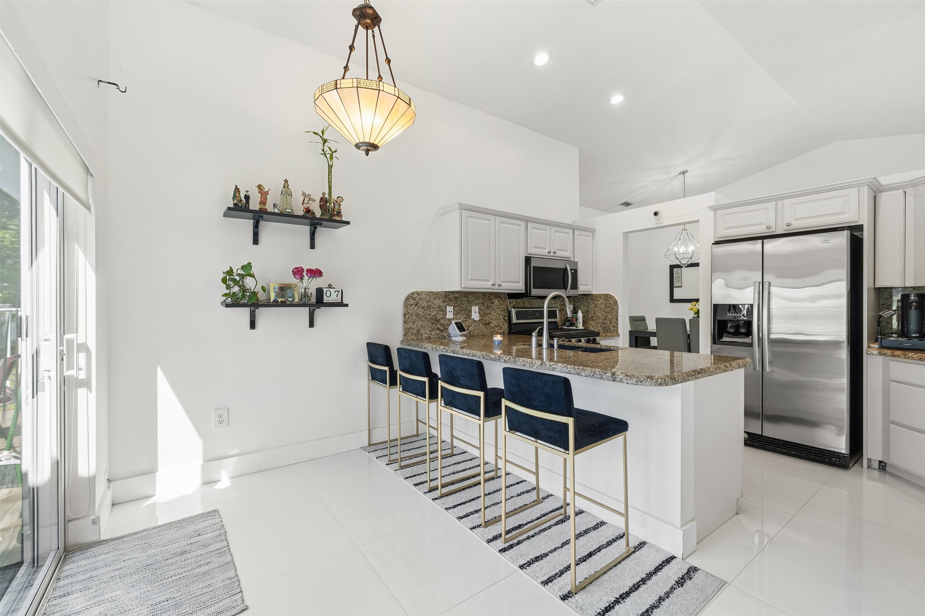 75 Gables Boulevard Weston, FL 33326 - Photo 8 of 29 Kitchen featuring decorative backsplash, lofted ceiling, a kitchen breakfast bar, stainless steel appliances, and light stone countertops