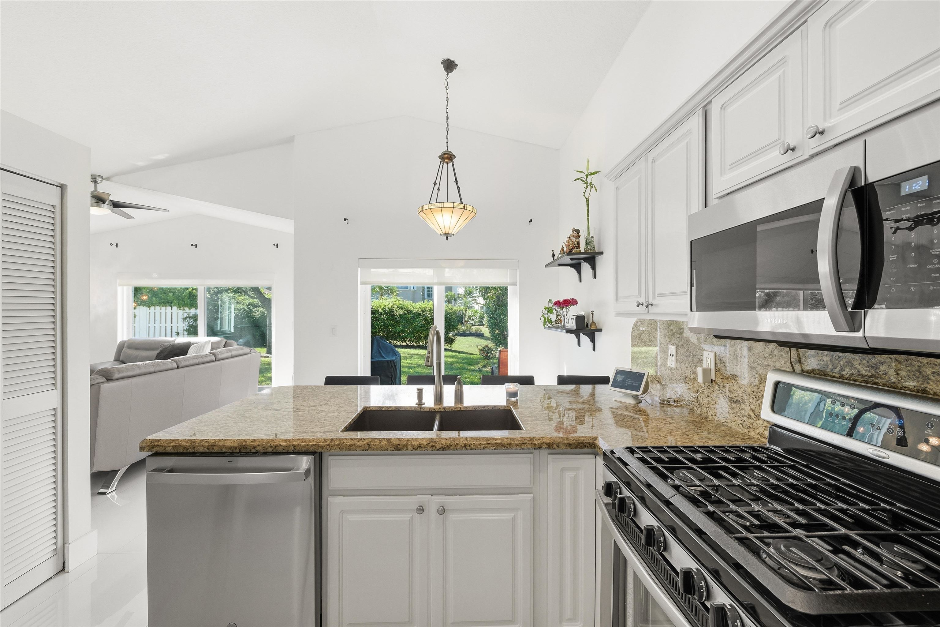 75 Gables Boulevard Weston, FL 33326 - Photo 27 of 29 Kitchen featuring stainless steel appliances, white cabinets, a peninsula, open floor plan, and hanging light fixtures