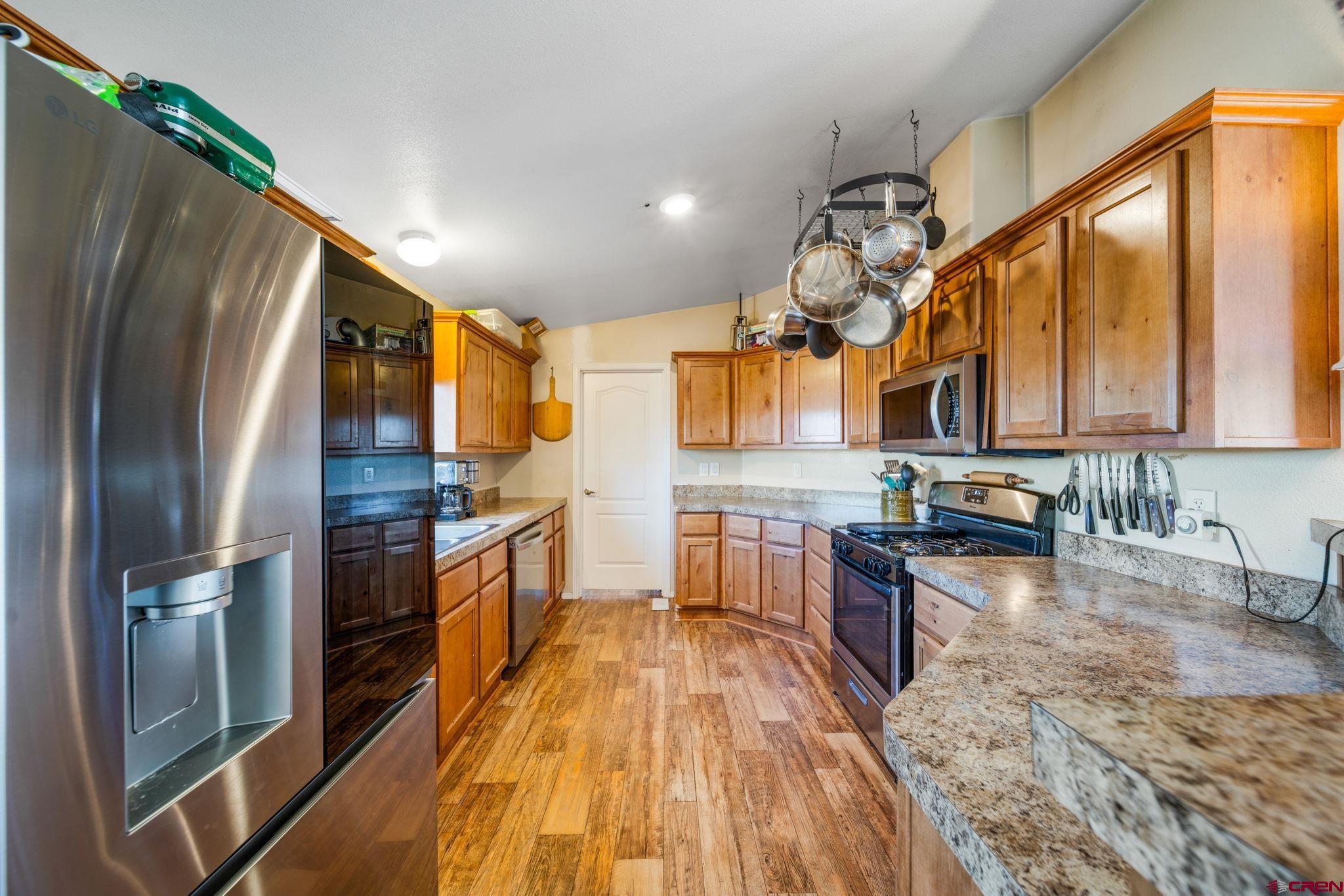 75 Sundial Lane Ignacio, CO 81137 - Photo 5 of 31 a kitchen with stainless steel appliances granite countertop a refrigerator a sink dishwasher a stove and white countertops with wooden floor
