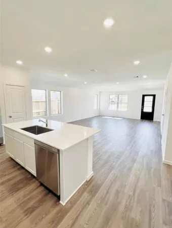 a large white kitchen with wooden floor and a sink