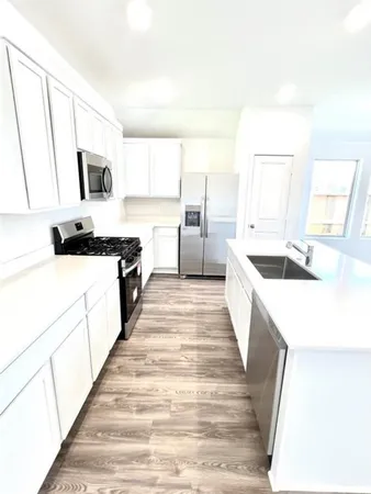 a large white kitchen with a stove a sink and a refrigerator