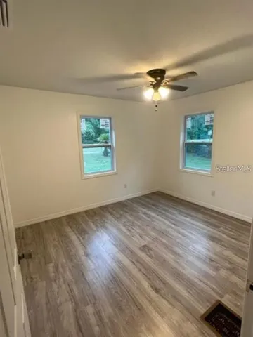 a view of empty room with wooden floor and fan
