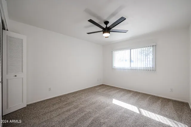 a view of a big room with wooden floor ceiling fan and windows
