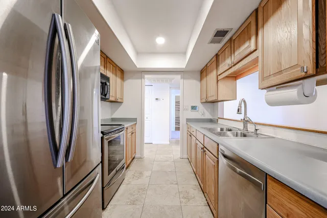 a kitchen with stainless steel appliances granite countertop a refrigerator a stove and a sink