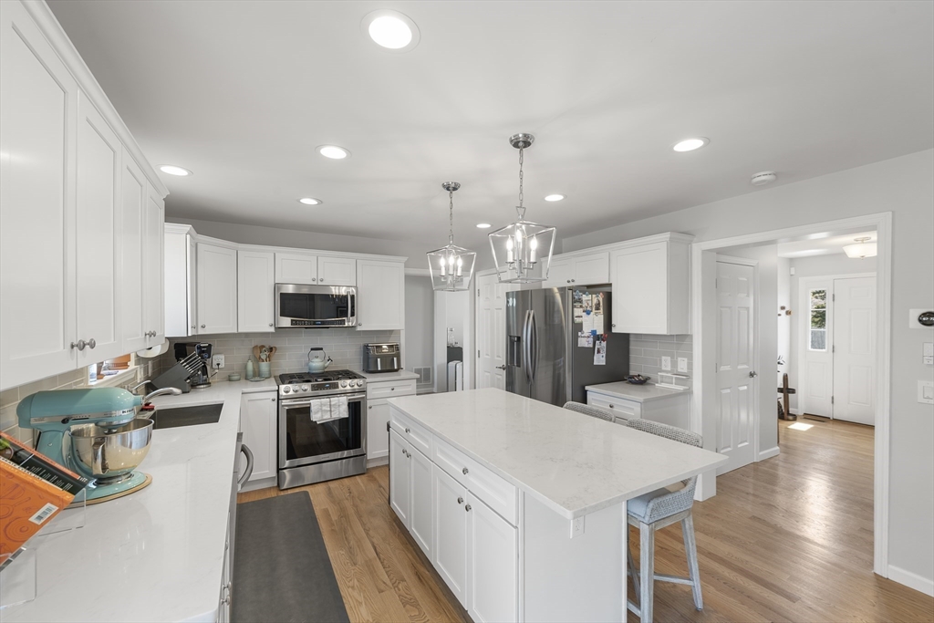 106 Colonial Road Marshfield, MA 02050 - Photo 3 of 16 a large kitchen with cabinets a sink dishwasher a stove and a refrigerator with wooden floor