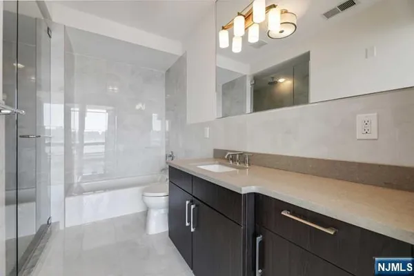 a bathroom with a sink a toilet a mirror and shower