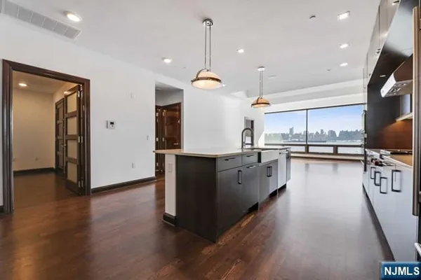 a kitchen with kitchen island stainless steel appliances a stove top oven a sink a refrigerator and wooden floor