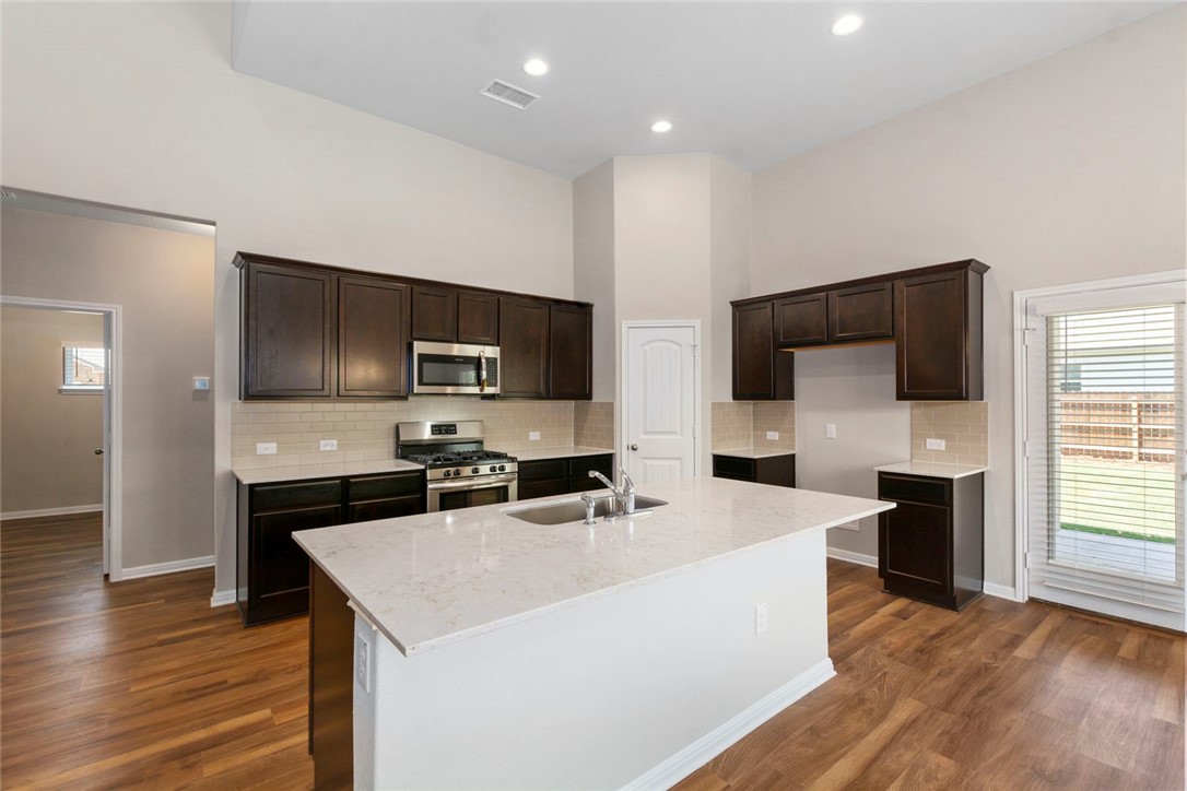 4217 Porter Farm Road Georgetown, TX 78628 - Photo 3 of 17 a kitchen with stainless steel appliances a stove top oven a sink a microwave and wooden floor