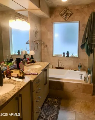 a bathroom with a double vanity sink a mirror and bathtub