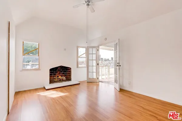 a view of empty room with wooden floor and fan