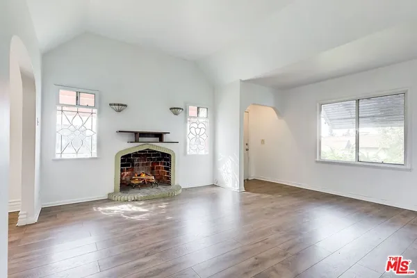 an empty room with windows a fireplace and wooden floor