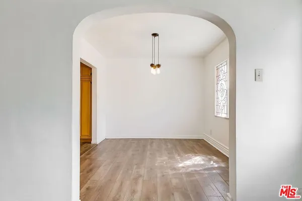 a view of empty room with wooden floor fireplace and window