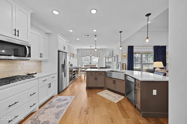 a large kitchen with stainless steel appliances kitchen island granite countertop a stove and a sink