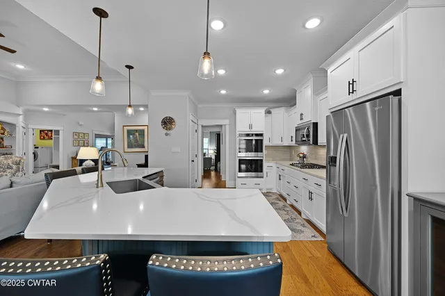 a large kitchen with stainless steel appliances a large center island attached withe living room