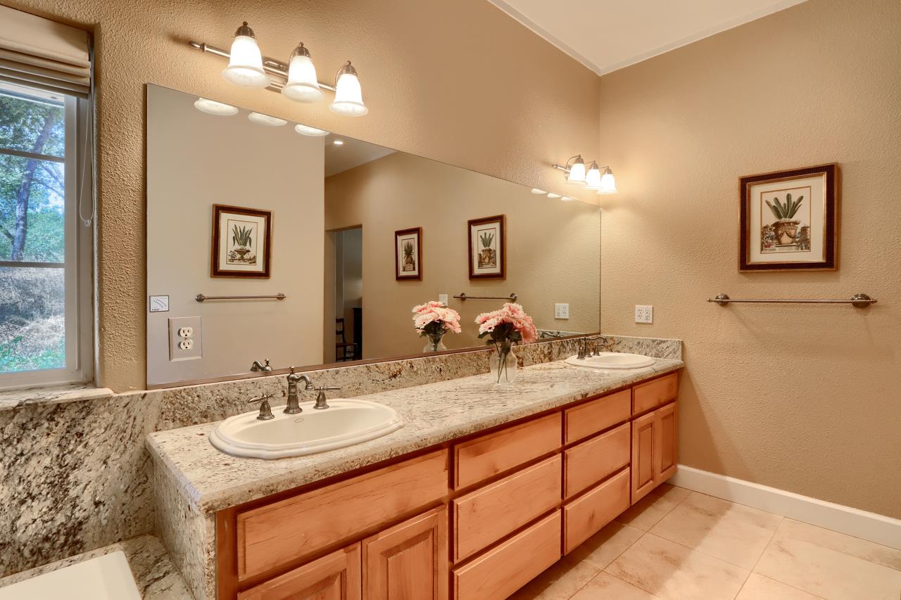 7551 Hunters Valley Road Mariposa, CA 95338 - Photo 35 of 78 a bathroom with a granite countertop sink a light fixture and a mirror