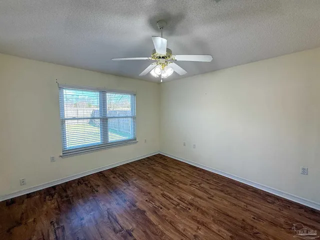 an empty room with wooden floor chandelier fan and windows