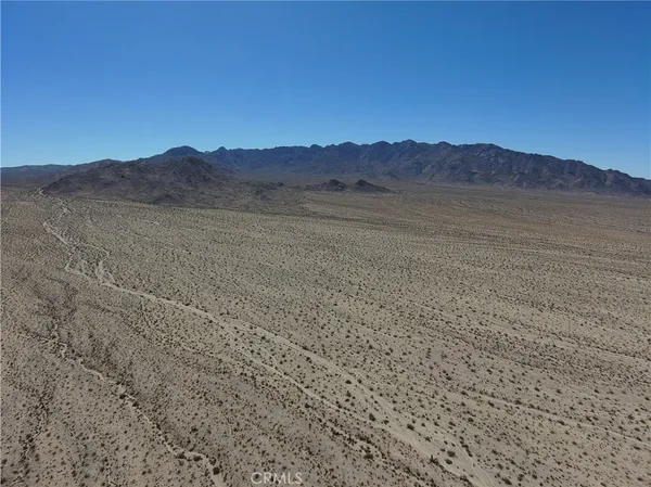 a view of a dry field with mountains in the background