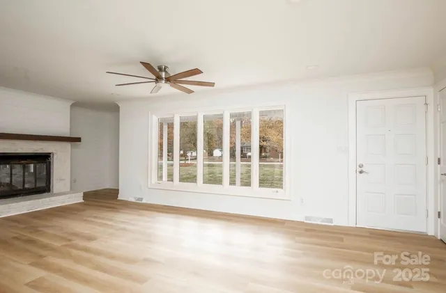 a view of an empty room with a window and a kitchen