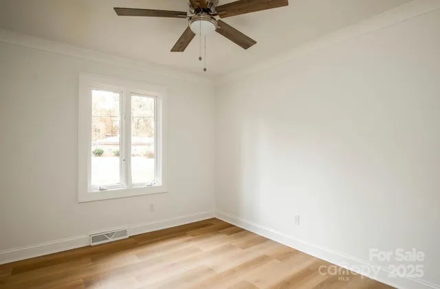 an empty room with a window and a fan