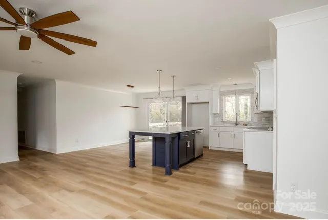 a kitchen with stainless steel appliances kitchen island granite countertop a sink cabinets and wooden floor