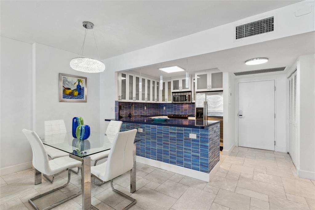 2301 Collins Avenue, Unit 1015 Miami Beach, FL 33139 - Photo 5 of 15 a kitchen with a dining table chairs and a refrigerator