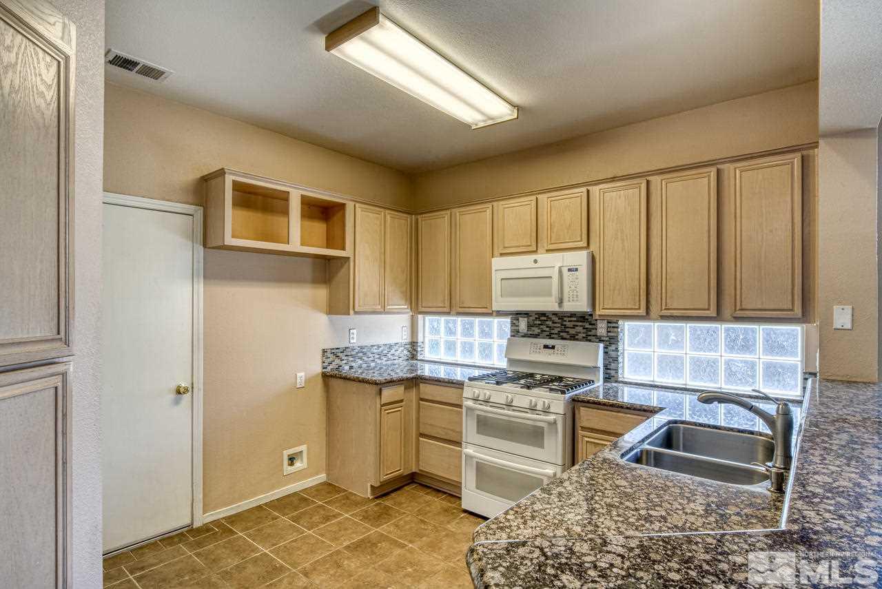 9683 Truckee Meadows Place Reno, NV 89521 - Photo 5 of 33 a kitchen with stainless steel appliances granite countertop a sink stove refrigerator and cabinets