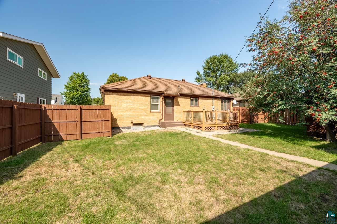 716 South 9th Street Virginia, MN 55792 - Photo 34 of 43 Spacious backyard with a wooden deck, privacy fencing, and mature trees
