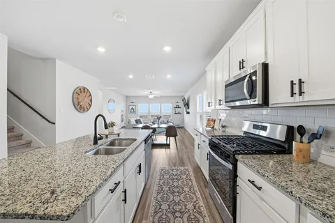 a kitchen with stainless steel appliances granite countertop a sink stove and refrigerator