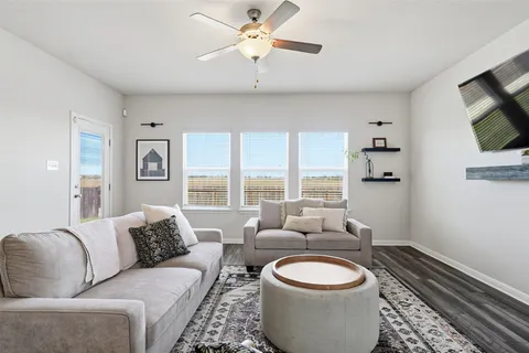 a living room with furniture a flat screen tv and a floor to ceiling window