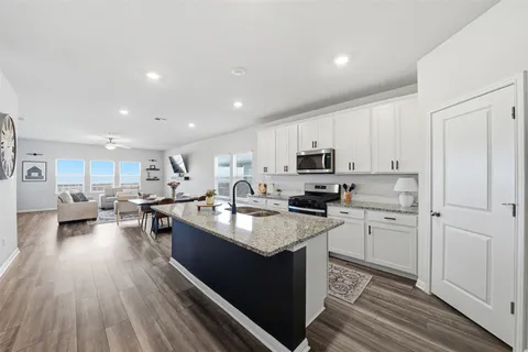 a large kitchen with stainless steel appliances granite countertop a lot of counter space and wooden floor