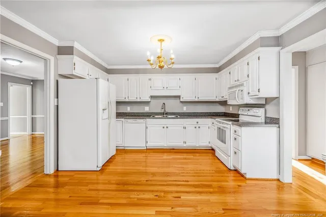 a kitchen with stainless steel appliances granite countertop a stove a sink dishwasher and a refrigerator with wooden floor