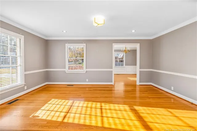 a view of an empty room with window and wooden floor