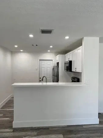 a view of a kitchen with stainless steel appliances wooden floor and large window