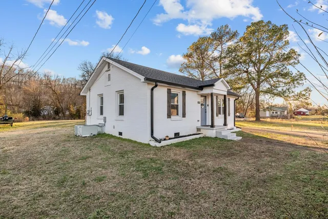 a view of a house with backyard and trees