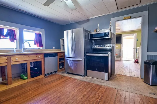 a kitchen with stainless steel appliances granite countertop a refrigerator a stove and a wooden floors