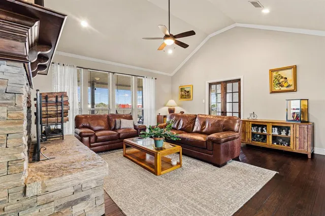 a large kitchen with granite countertop a stove a sink a refrigerator white cabinets and wooden floor