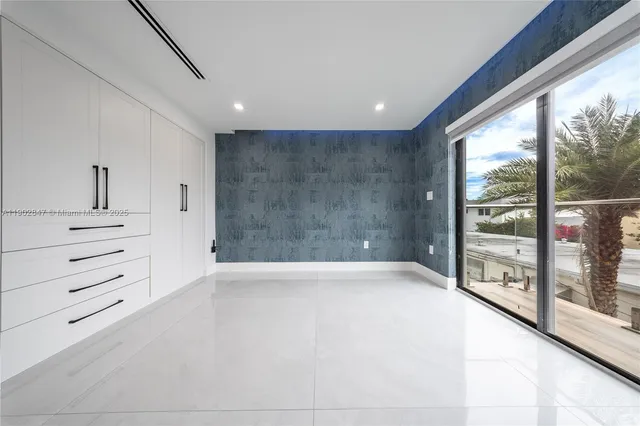 a bed sitting in a spacious bedroom next to a window