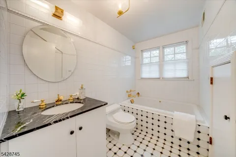 a bathroom with a granite countertop sink a toilet and a mirror