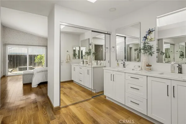 a spacious bathroom with a double vanity sink a mirror and next to a window