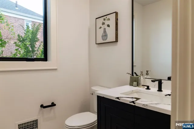 a bathroom with a granite countertop toilet sink and mirror
