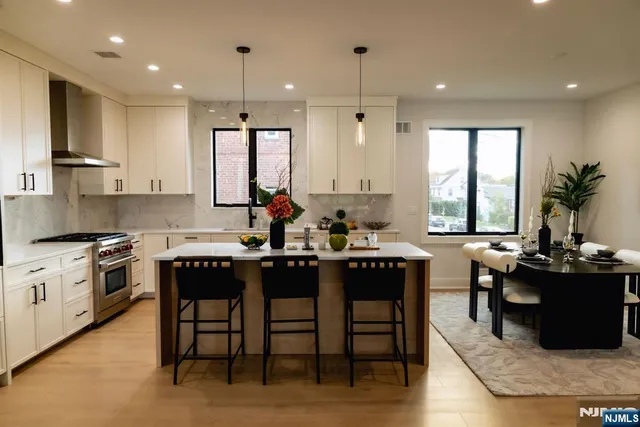 a kitchen with stainless steel appliances granite countertop sink stove and white cabinets with wooden floor