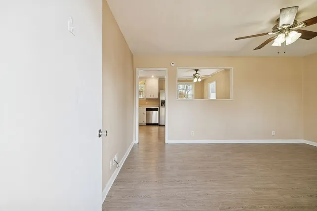 an empty room with wooden floor fan and windows