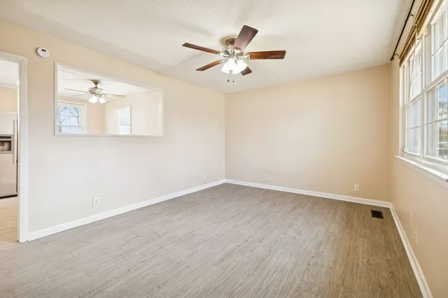 an empty room with wooden floor and ceiling fan